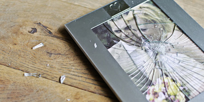 zerbrochener Rahmen mit Hochzeitsfoto liegt auf dem Holzfußboden