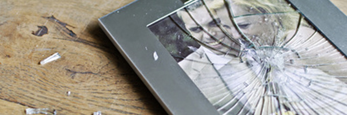 zerbrochener Bilderrahmen mit Hochzeitsfoto auf dem Boden