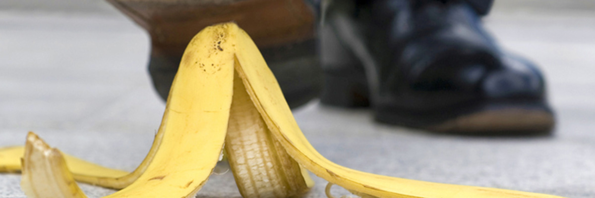 Männerschuh tritt auf Bananenschale auf dem Boden.