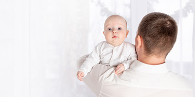 a father holds a newborn baby on his shoulder at home by the window, the concept of a happy loving family, father's day